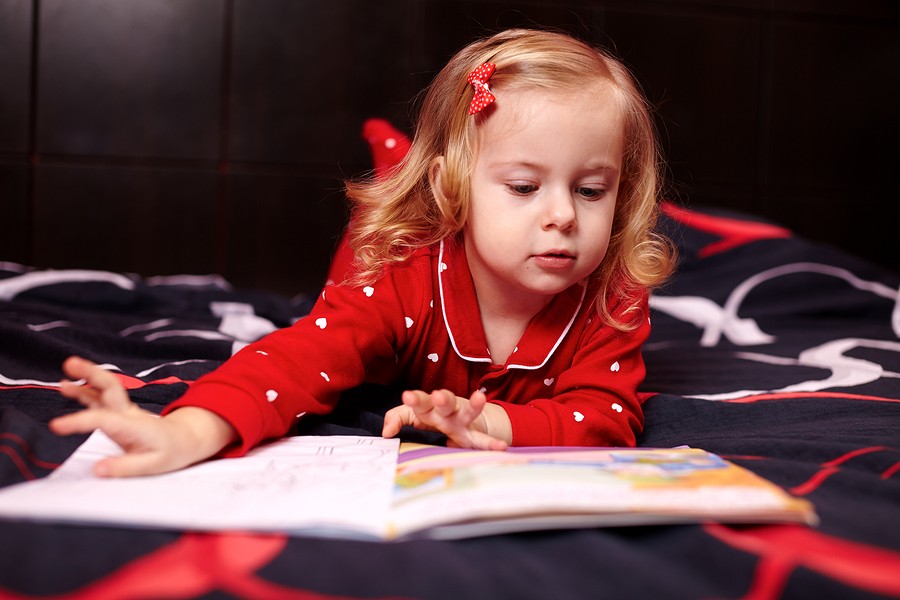 Cute Girl Reading A Book On The Bed